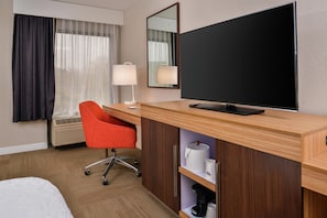A hotel room with a bed, a desk with a chair, a television, and a window with curtains. - Hampton Inn Raleigh/Clayton I-40 (Garner)
