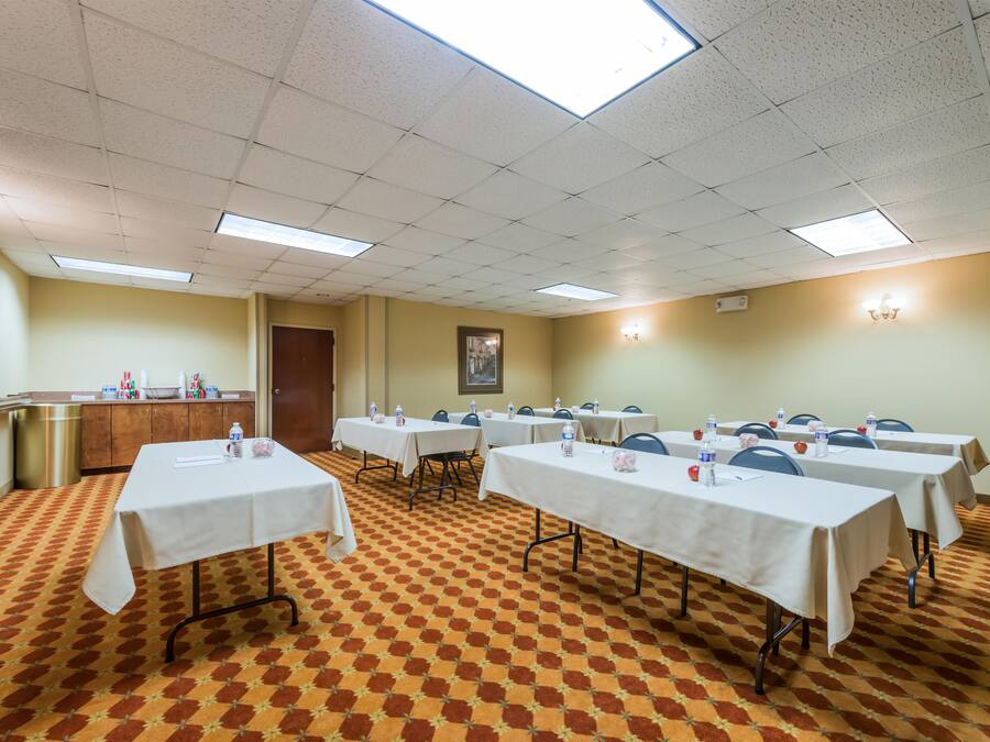 A conference room with multiple tables, chairs, and a patterned carpet.