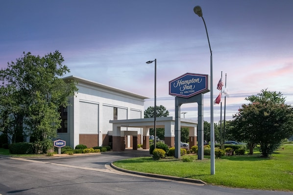 A Hampton Inn by Hilton sign, a clear entrance, and a welcoming archway.