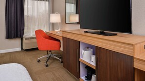 A hotel room with a wooden desk, a red chair, a flat-screen TV, a mirror, and a bed. - Hampton Inn Raleigh/Clayton I-40 (Garner)