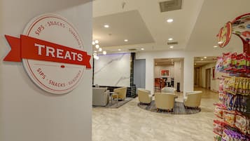 A hotel lobby with a 'Treats' sign, seating area, and snack display.
