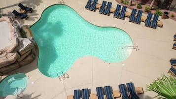 A swimming pool with lounge chairs and a hot tub area.
