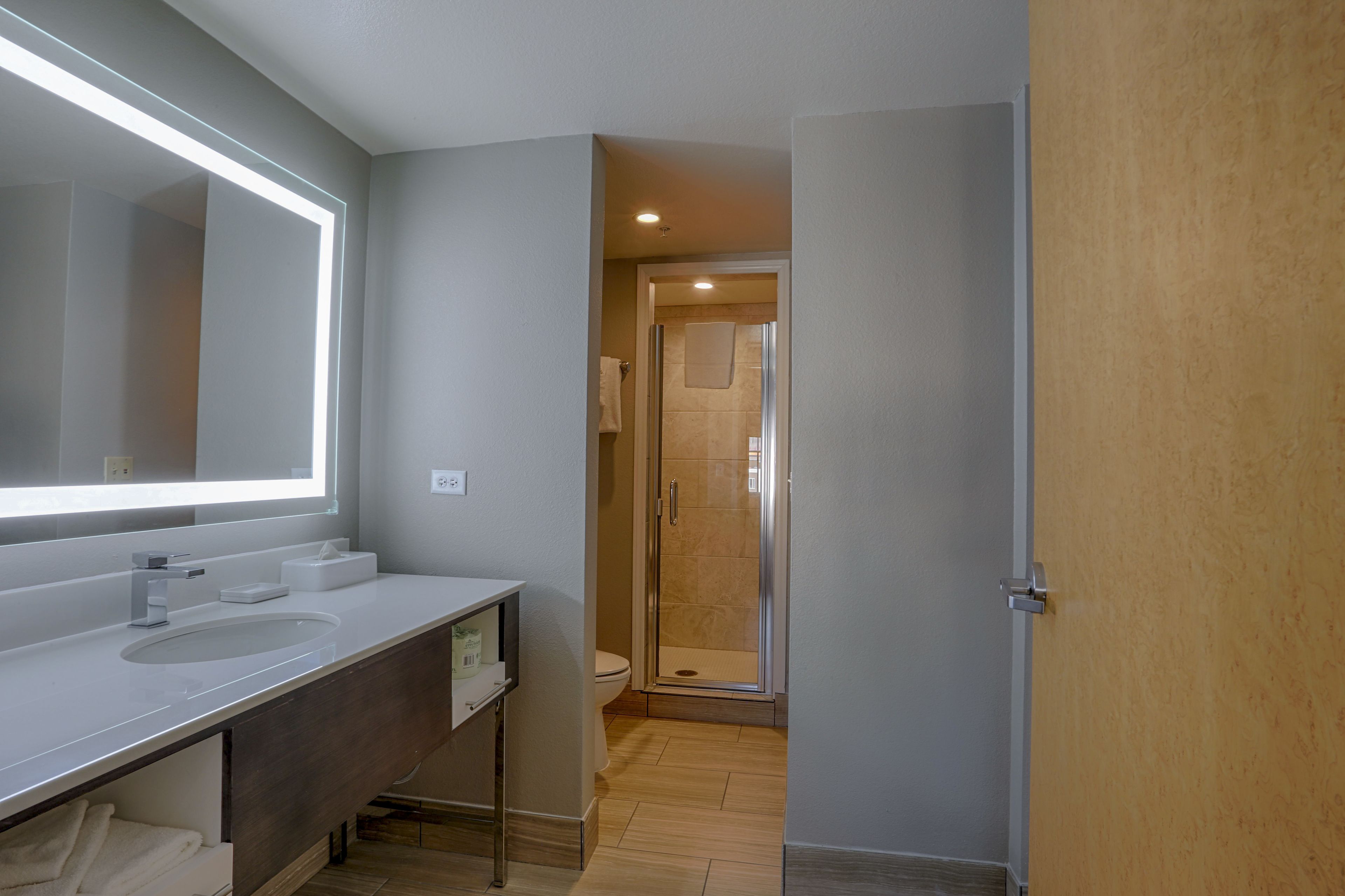 Un baño moderno con un espejo grande, un lavabo y una zona de ducha.