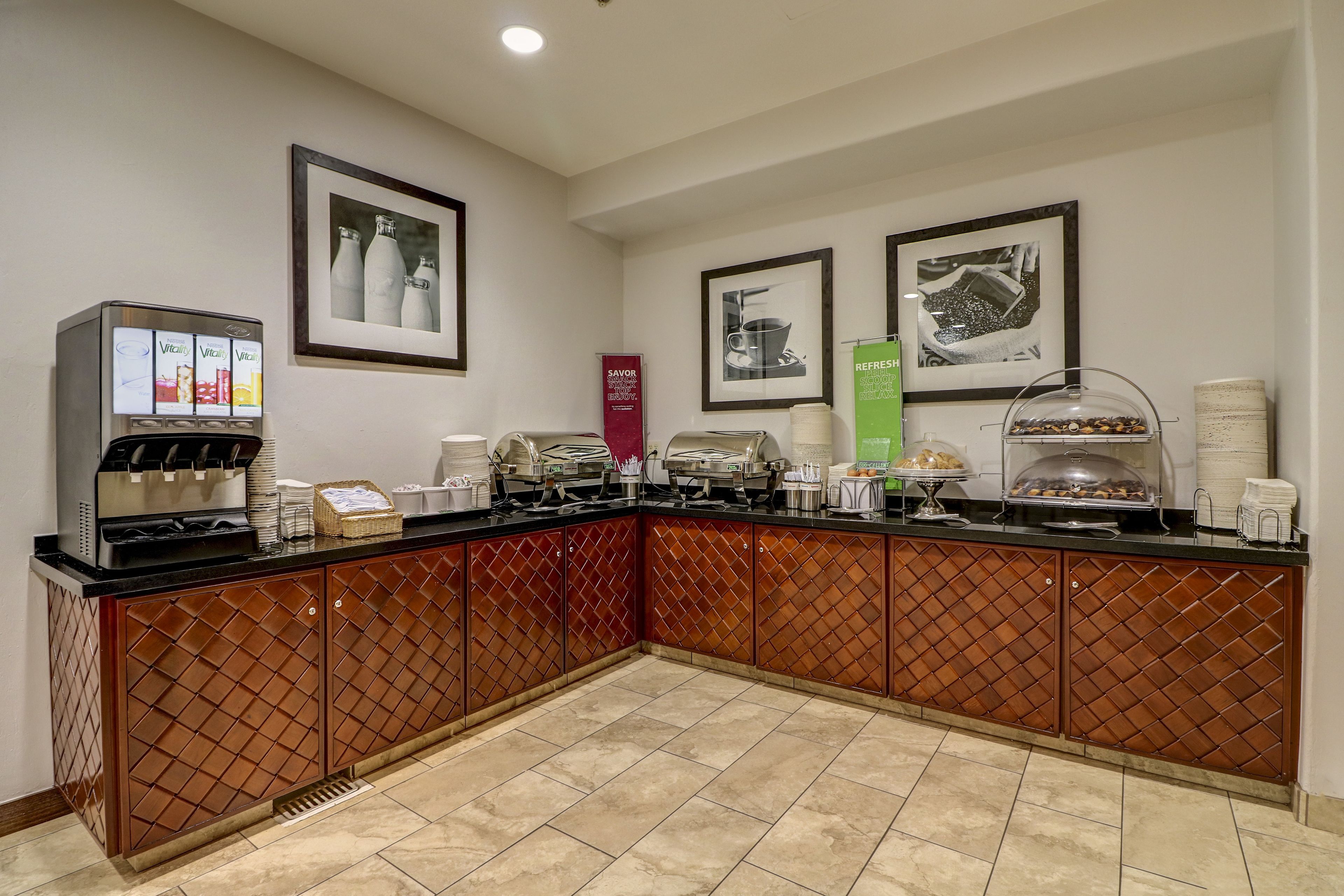 A self-service breakfast bar with coffee machines, tea dispensers, and a variety of food options.