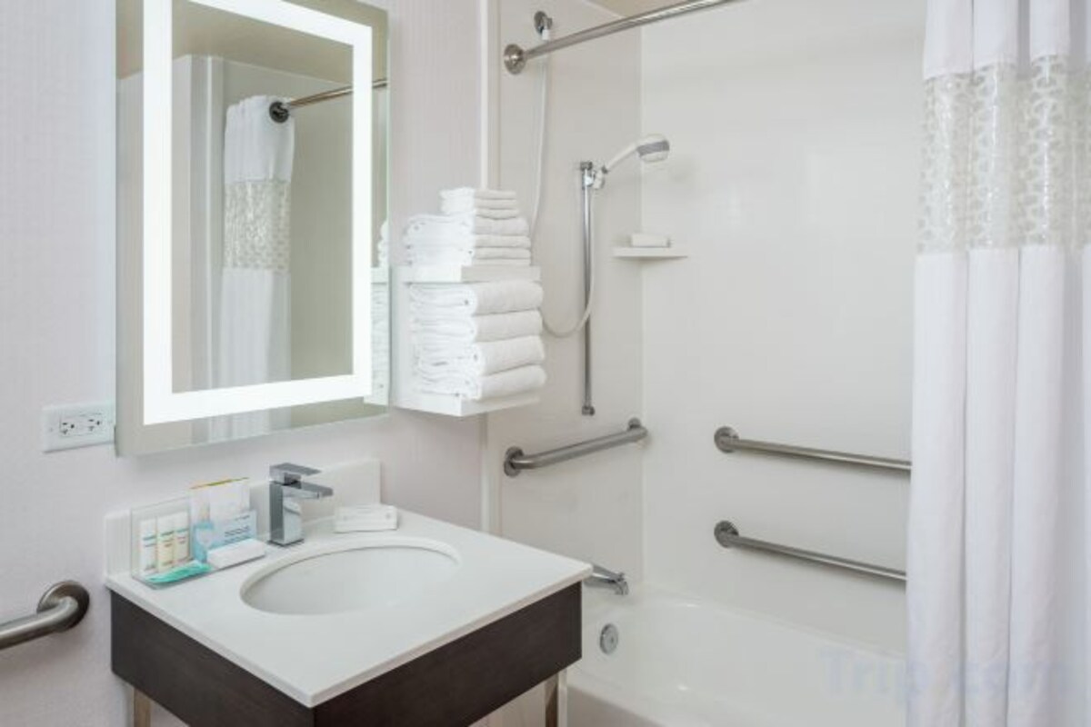 A bathroom with a sink, mirror, and shower.
