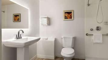 Une salle de bain avec un lavabo, des toilettes et une douche. Deux tableaux encadrés sont accrochés au mur.