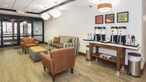 A lobby with seating, a coffee station, and a trash can.