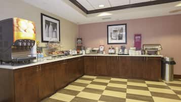 A breakfast bar with a juice dispenser, coffee maker, and a trash can.