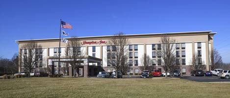 Hotel Hampton Inn con estacionamiento y una bandera al frente.