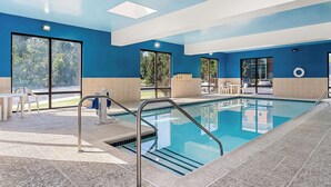 Ein Innenpool mit großen Glaswänden, einer blauen und beigen Farbgestaltung und einem Oberlichtholz.