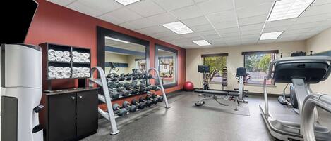 Une salle de sport équipée de tapis de course, d’haltères et d’un banc de musculation.
