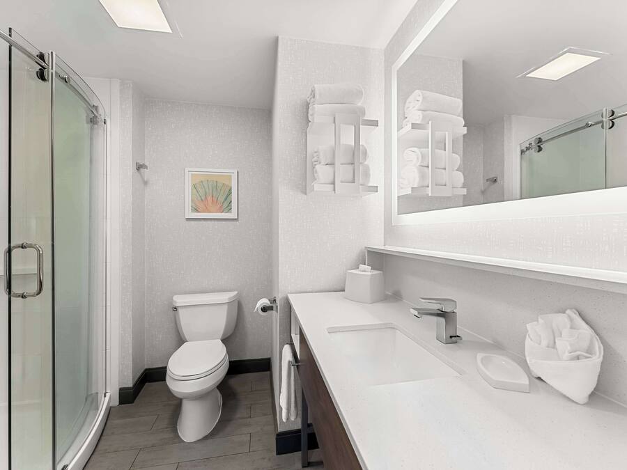A modern bathroom with a glass shower enclosure, a toilet, a sink with a mirror, and a towel rack.