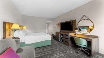 A hotel room with a bed, a desk with a chair, a television, and a mirror.