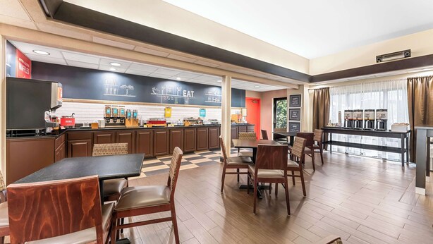 Ein Hotelrestaurant mit Schachbrettfußboden, Holzmöbeln und einer Theke mit verschiedenen Speisen.