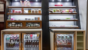Uma área de distribuição com lanches e bebidas, incluindo uma placa 'VA' e uma placa 'TREATS' acima das prateleiras.