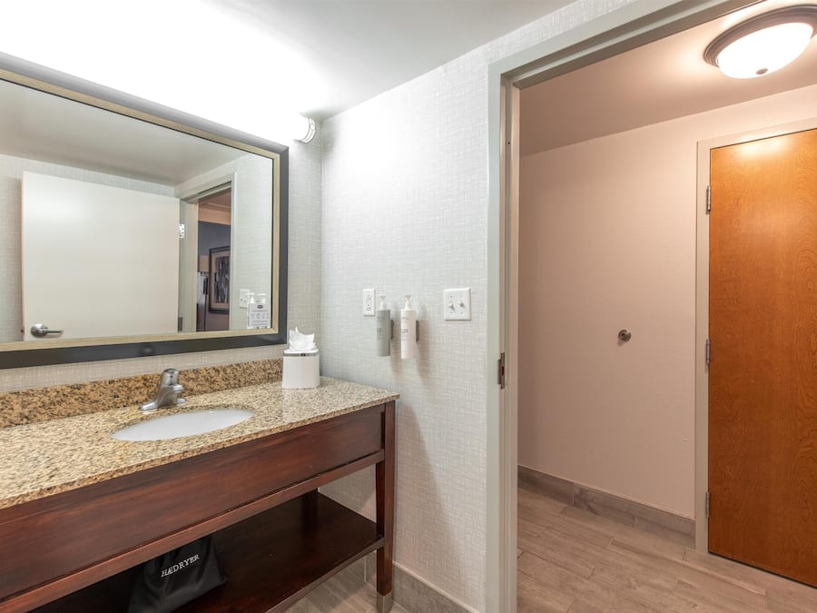 Une salle de bain avec un lavabo en granit, un miroir et un meuble-lavabo en bois.