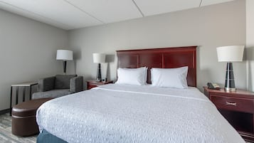 Habitación de hotel con una cama grande, dos mesitas de noche, una silla y dos lámparas.