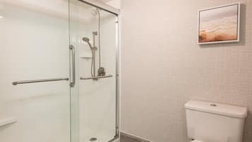 Ein Badezimmer mit einer Duschkabine aus Glas, einer Toilette und einem gerahmten Bild an der Wand.