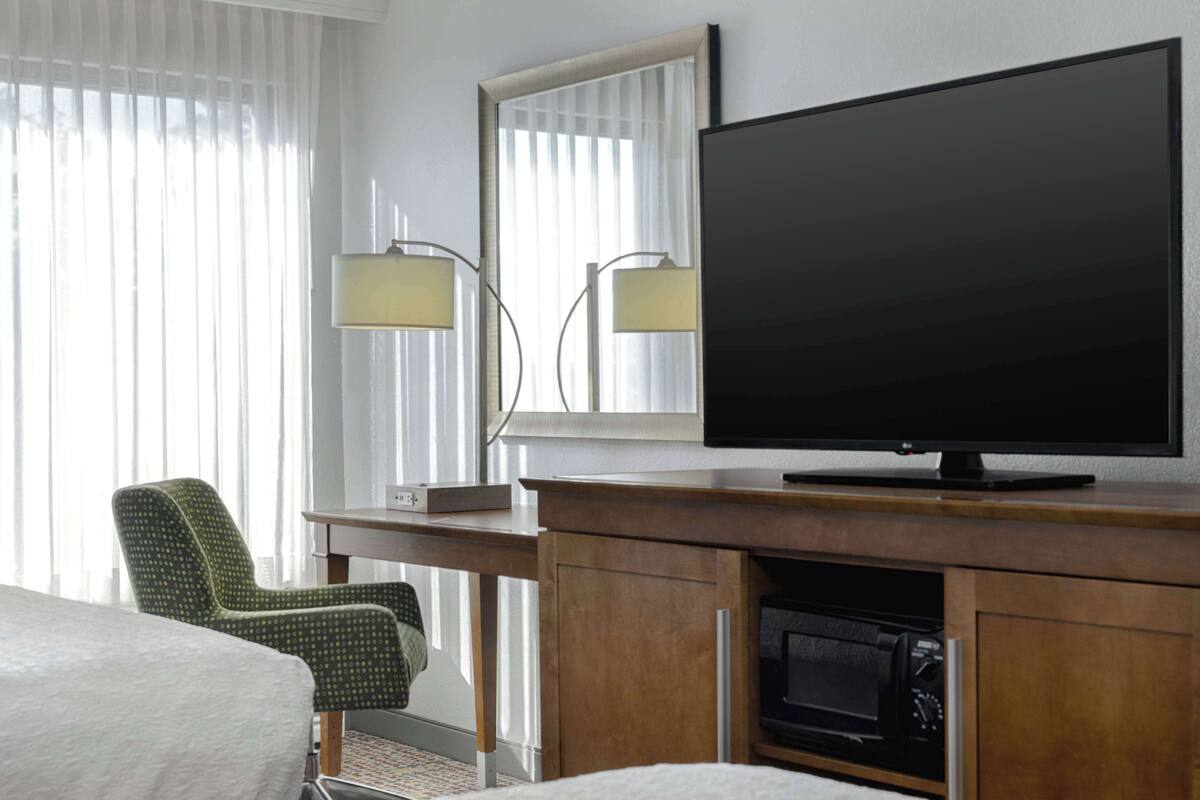A hotel room with a bed, a TV, a desk, and a chair.