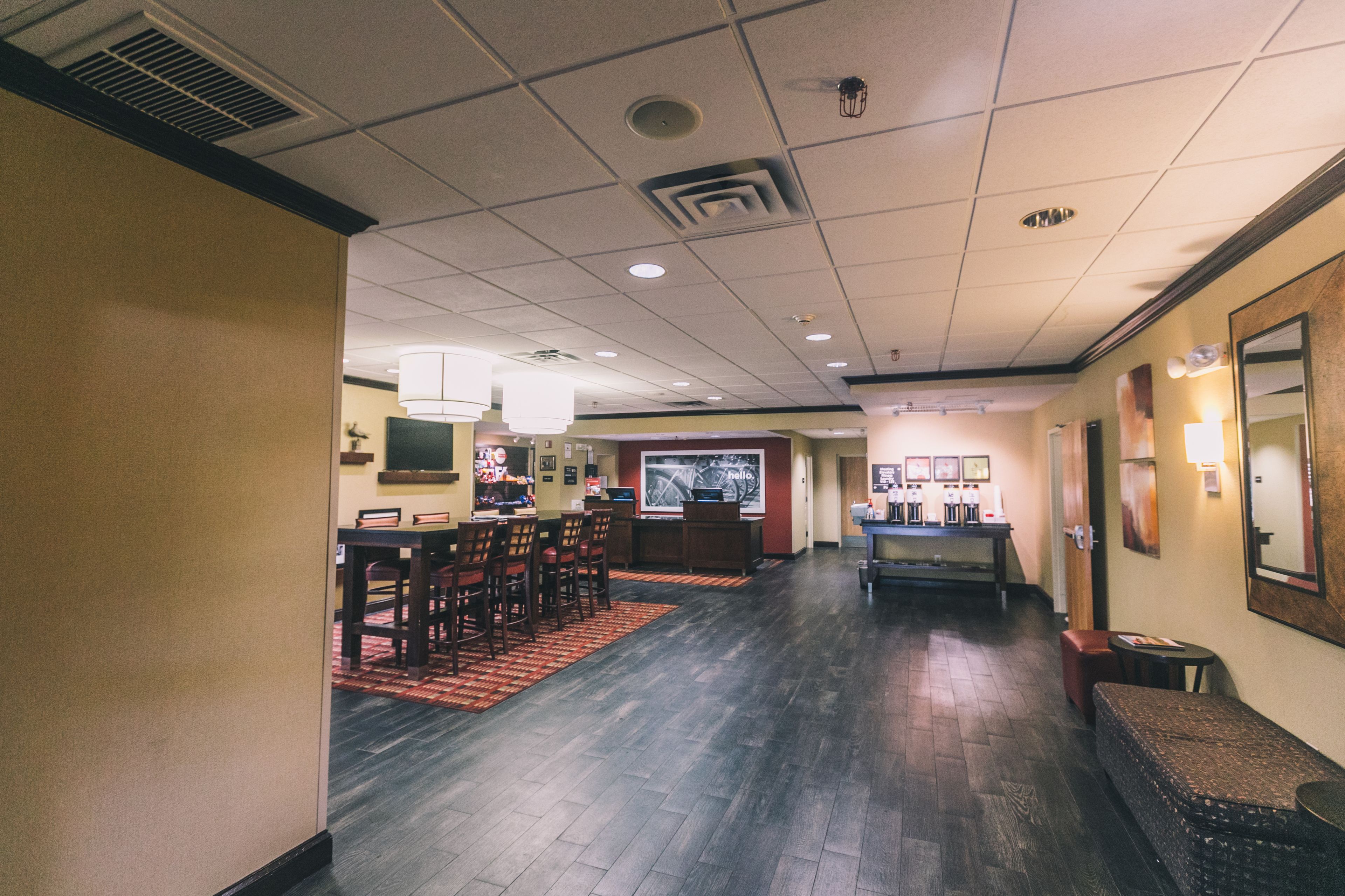 A hotel lobby with a reception desk, seating area, and a bar.