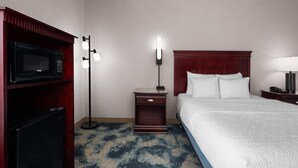 A hotel room with a bed, a microwave, a nightstand, a lamp, and a TV. - Hampton Inn Winfield/teays Valley (Hurricane)