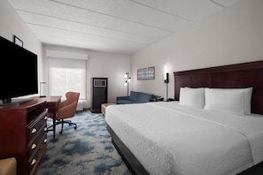 Una habitación de hotel con una cama grande, un escritorio, un televisor y un mueble para televisión.