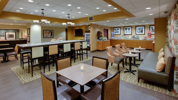 A hotel lobby with a bar area, seating arrangements, and a television screen. - Hampton Inn Winfield/teays Valley (Hurricane)