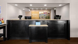 A reception desk with a 'welcome to Hampton' sign, a 'Hilton Honors' plaque, and a digital kiosk. - Hampton Inn Winfield/teays Valley (Hurricane)