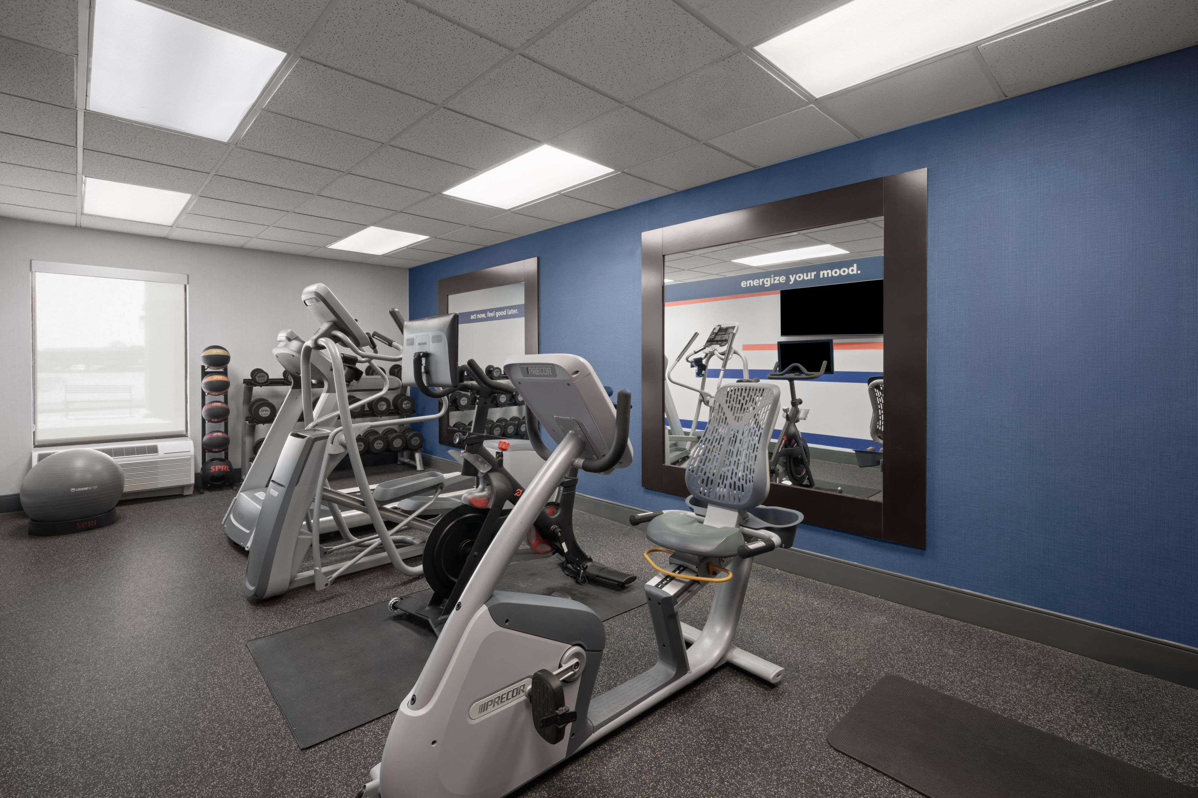 A gym with various exercise equipment, a mirrored wall, and a motivational slogan.