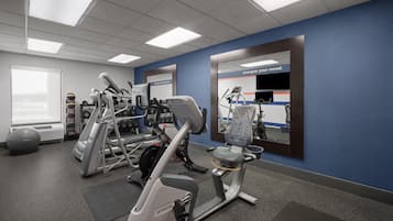 A gym with various exercise equipment, a mirrored wall, and a motivational slogan.