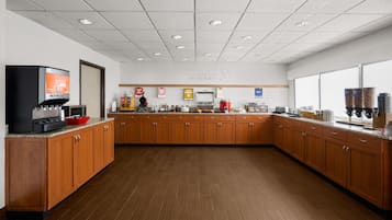 A spacious kitchen area with wooden cabinets, a coffee machine, and a breakfast bar.