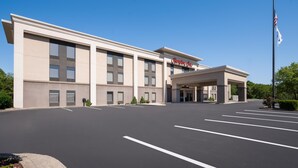 A modern hotel with a flat facade, a covered entrance, and a parking lot.