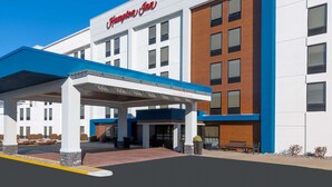 A modern hotel with a prominent "Hampton Inn" sign, a covered entrance, and a clean, welcoming facade.