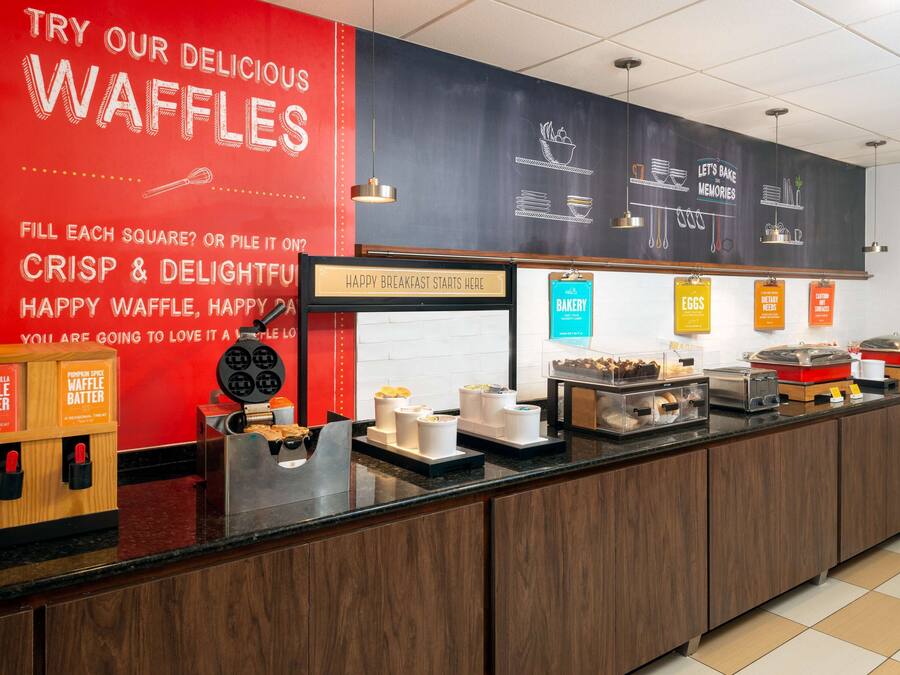 A breakfast bar with waffle stations and bakery items.