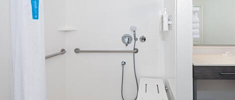 A shower with a handheld showerhead, a handheld faucet, and a grab bar.
