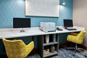 A workspace with two monitors, a printer, and a desk. There are two yellow chairs and a shelf with a vase and basket. - Hampton Inn & Suites Kansas City-Country Club Plaza (Kansas City)