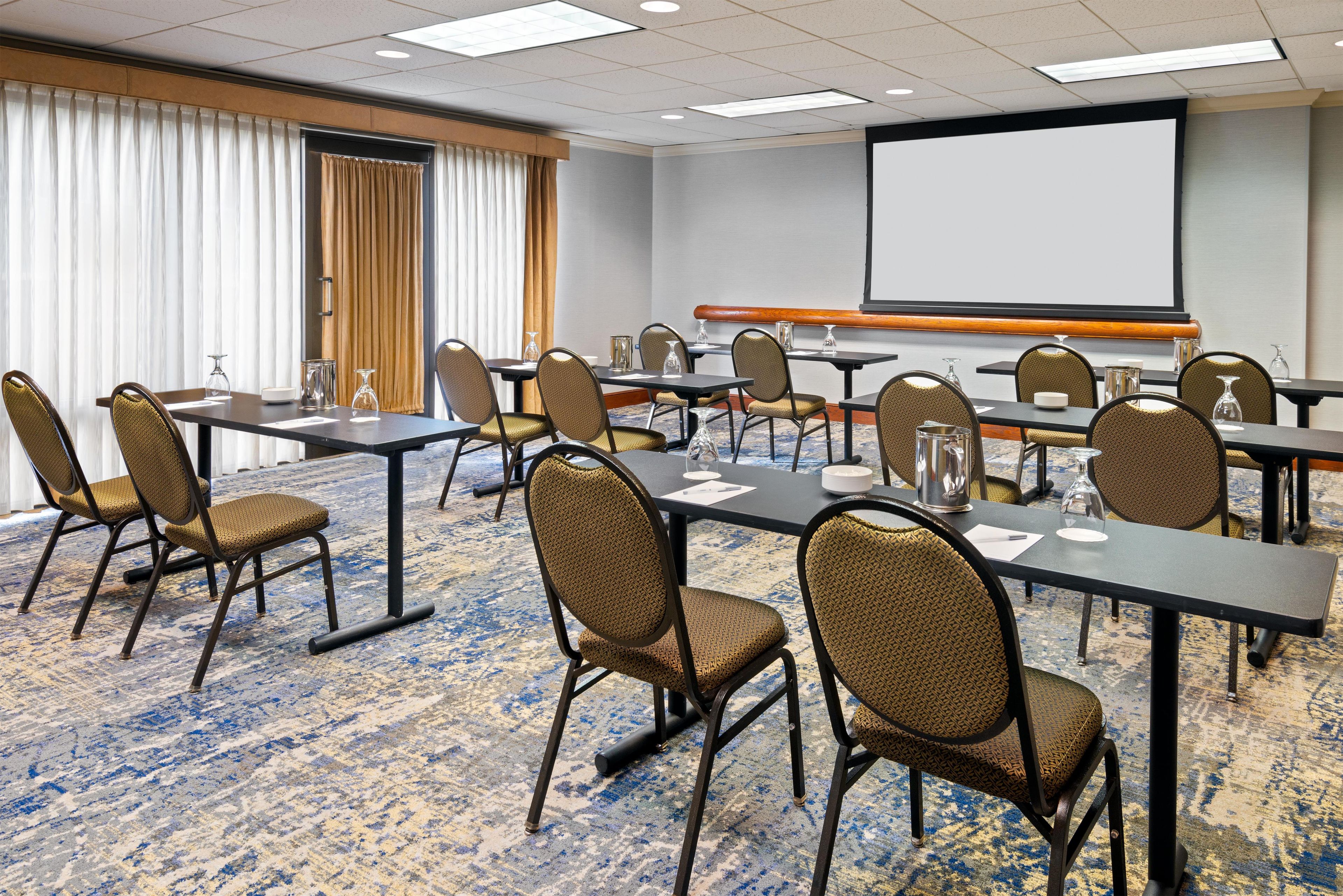 Une salle de conférence équipée d’un grand écran, de plusieurs tables et de chaises.