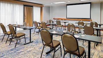 Une salle de conférence équipée d’un grand écran, de plusieurs tables et de chaises.