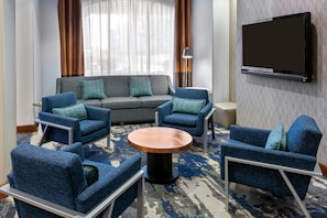 Ein modernes Hotelzimmer mit einer Sitzecke, Sesseln, einem Couchtisch und einem an der Wand montierten Flachbildfernseher.