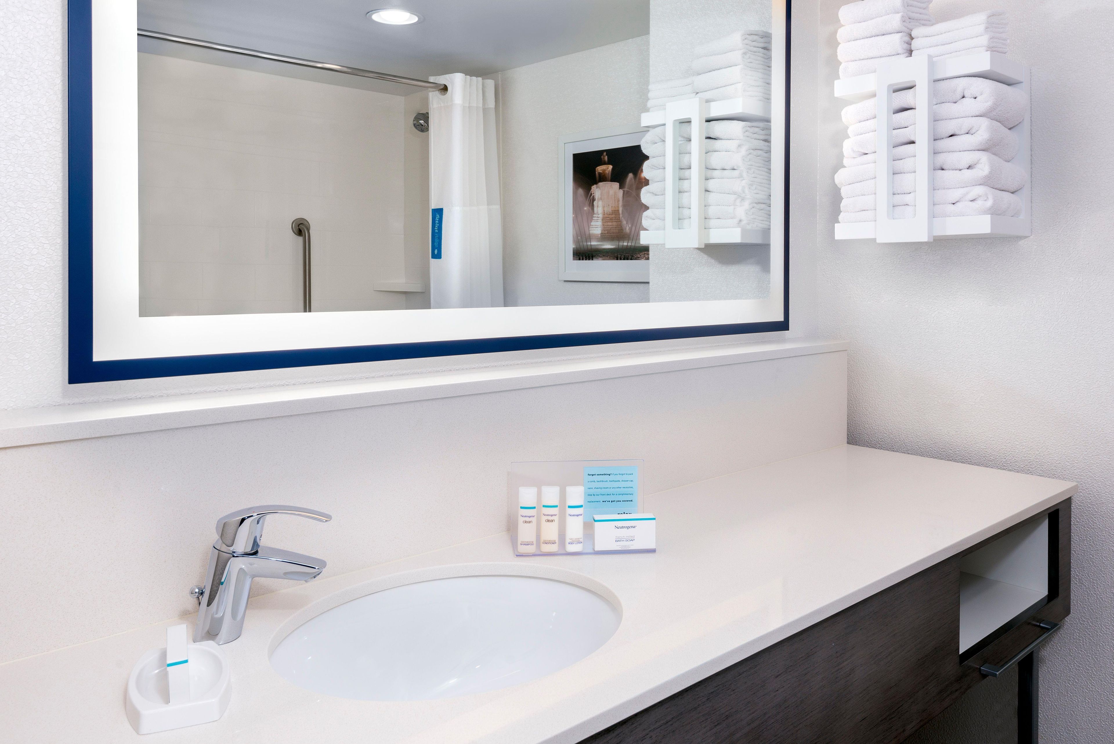 A bathroom with a large mirror, a sink, and a towel rack.