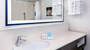 A bathroom with a large mirror, a sink, and a towel rack.