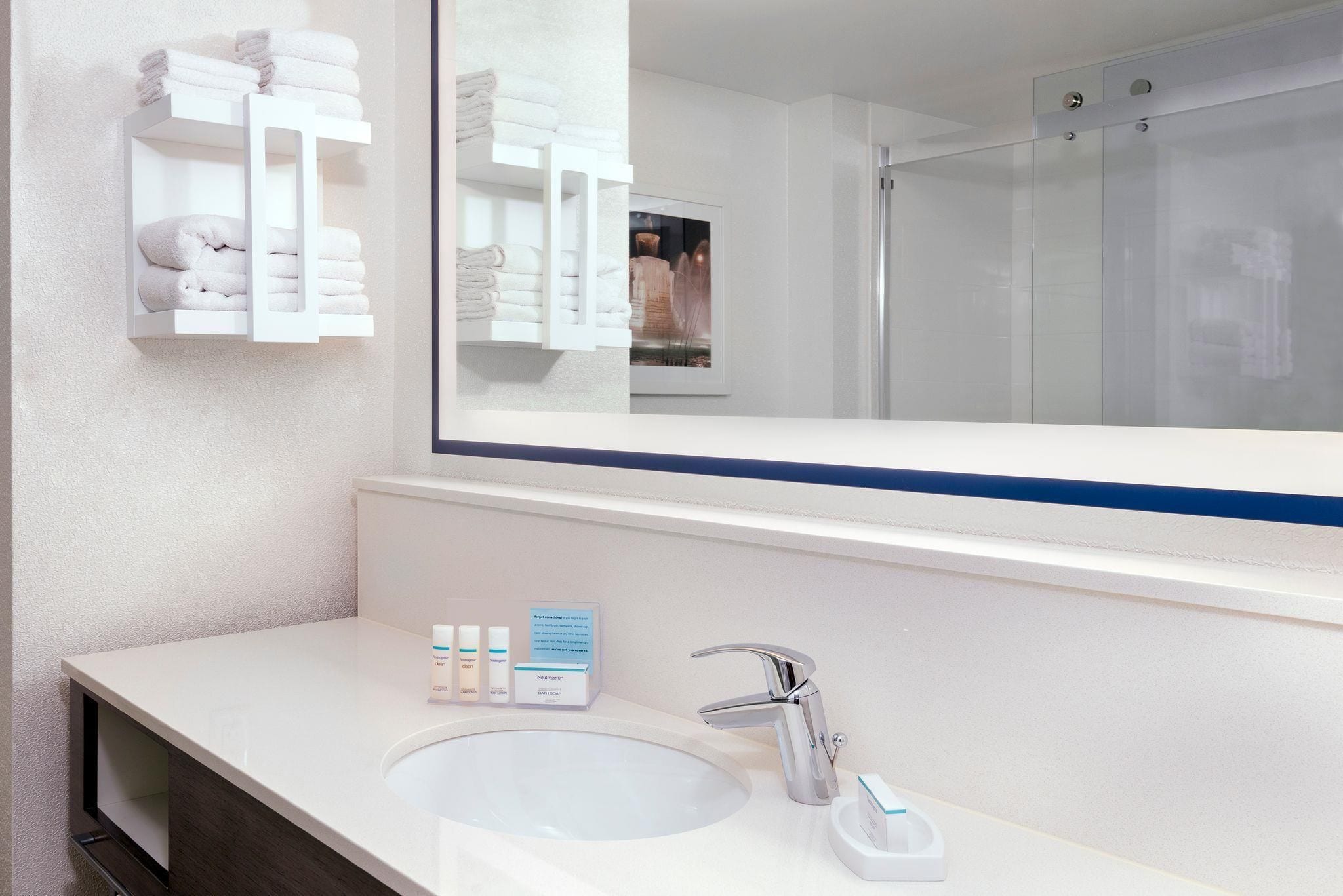 A bathroom with a white sink, a mirror, and a glass shower enclosure.