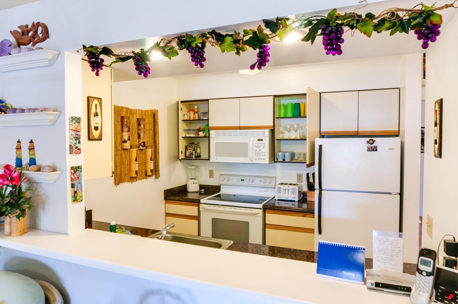 A kitchen with a microwave, stove, refrigerator, and various kitchen items.