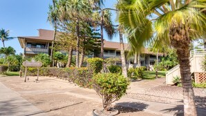 A hotel with a two-story building, palm trees, and a sign in the foreground.