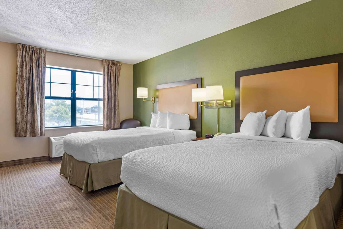 Een hotelkamer met twee bedden, een groot raam en uitzicht op de omgeving.
