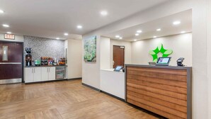 A reception area with a wooden reception desk, a coffee machine, and a wall-mounted phone.