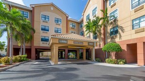 A hotel entrance with a clear sky, palm trees, and a sign indicating a lobby and 7'-0" max clearance.