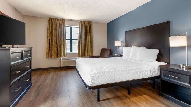 A modern hotel room with a large bed, a desk, a chair, a TV, and a window with curtains. - Extended Stay America Suites Fort Worth City View (Fort Worth)