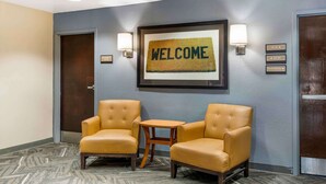 A hotel lobby with two yellow armchairs, a small wooden table, a welcome mat, and directional signs. - Extended Stay America Suites Fort Worth City View (Fort Worth)