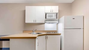 A compact kitchen with white cabinets, a microwave, a refrigerator, and a sink. - Extended Stay America Suites Fort Worth City View (Fort Worth)